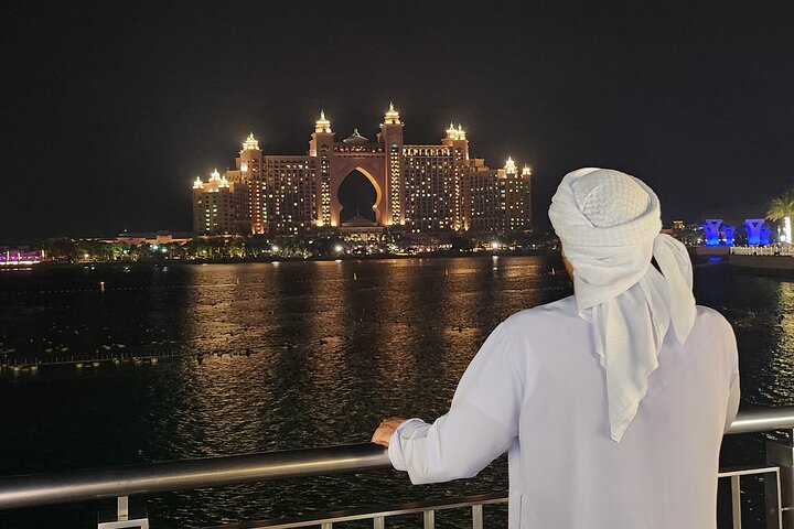 Experience the mesmerizing Dubai skyline at night with the iconic Atlantis shimmering in the background highlighting the city’s luxurious charm and culinary delights along the way.